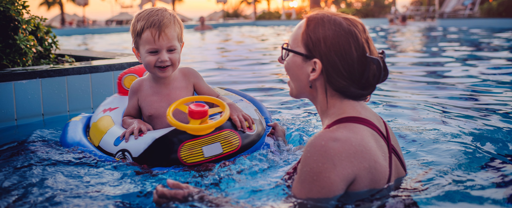 Mother talking to baby son on a pool float 