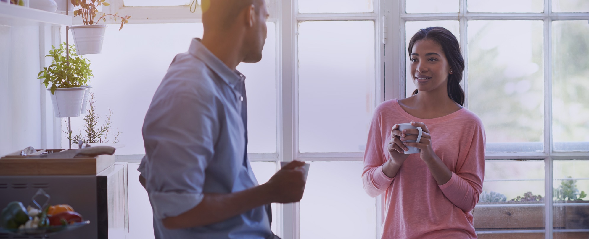 Man and woman standing in kitchen drinking coffee 