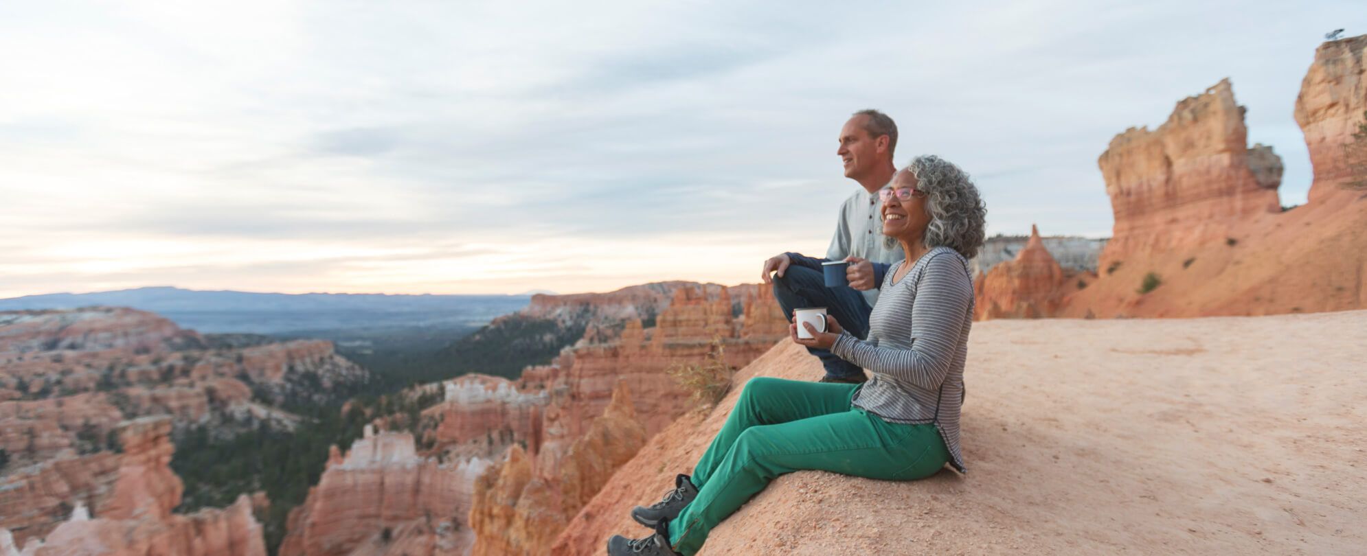 Couple sitting on the cliffs of red rocks 