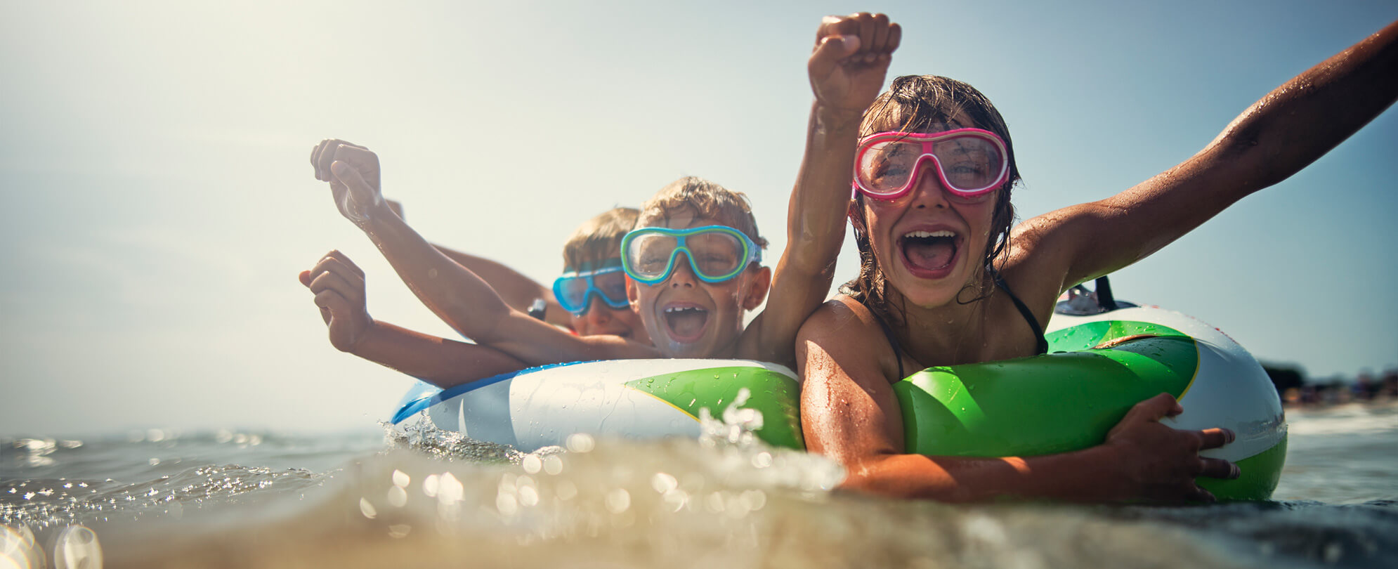Three kids wearing goggles splashing around in a swim float