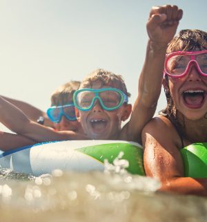 Three kids wearing goggles splashing around in a swim float