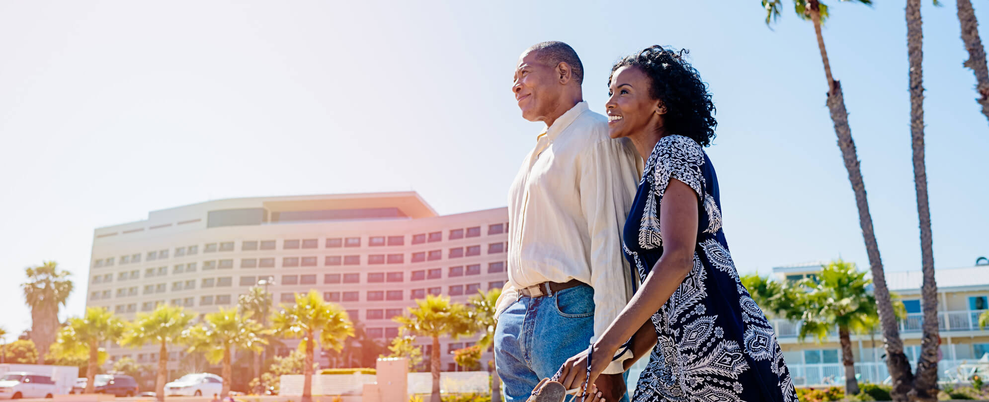 Couple holding each other in front of a resort and looking into the distance 