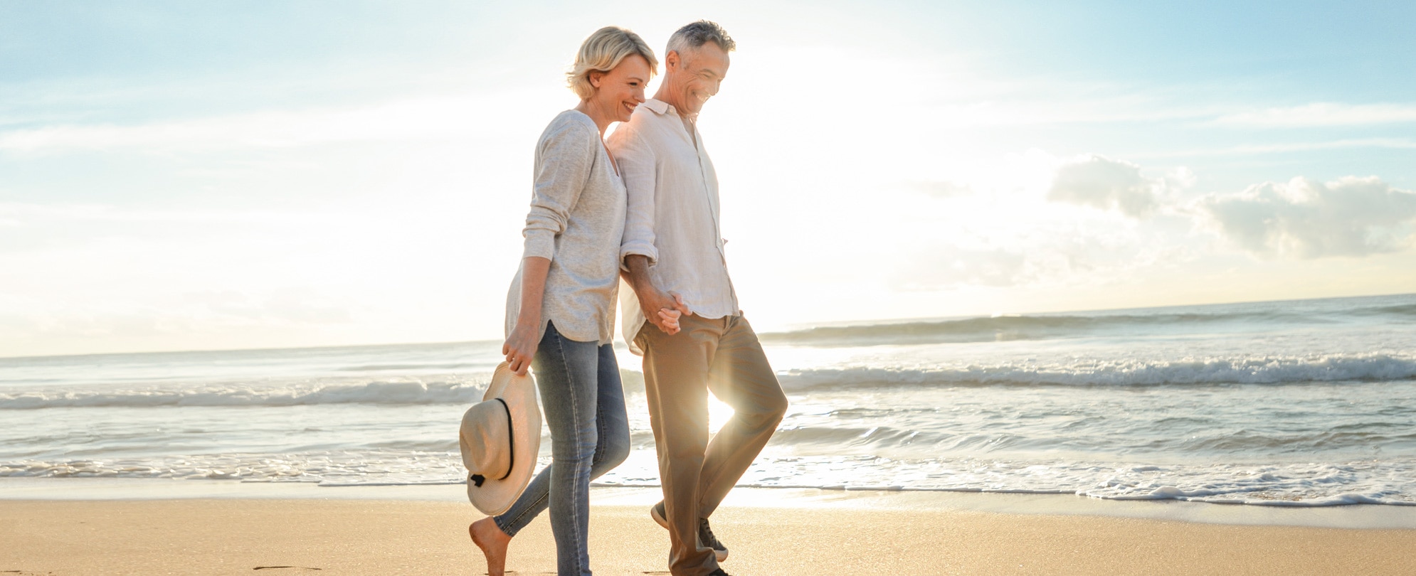 Couple holding hands walking along the beach 