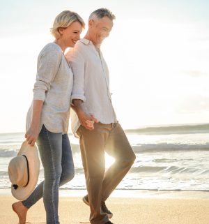 Couple holding hands walking along the beach 