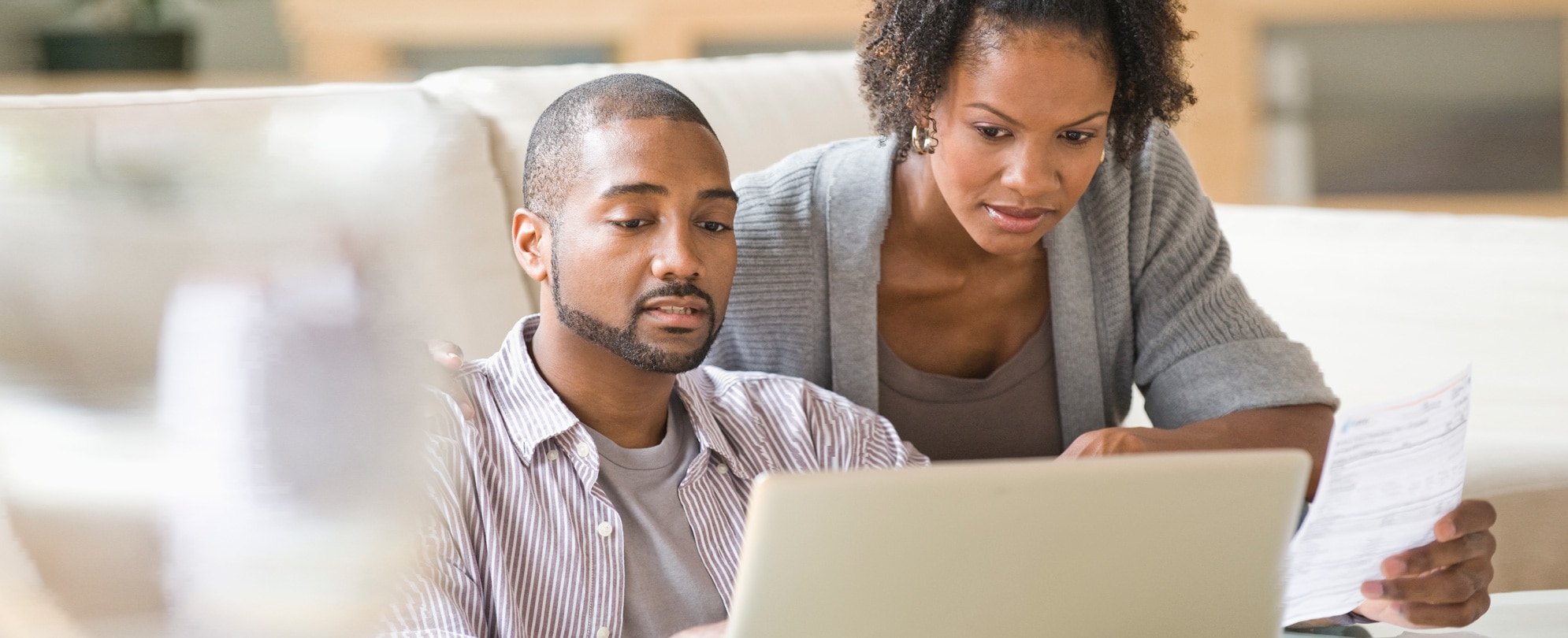 Worried African American couple reviewing timeshare documents on their laptop 