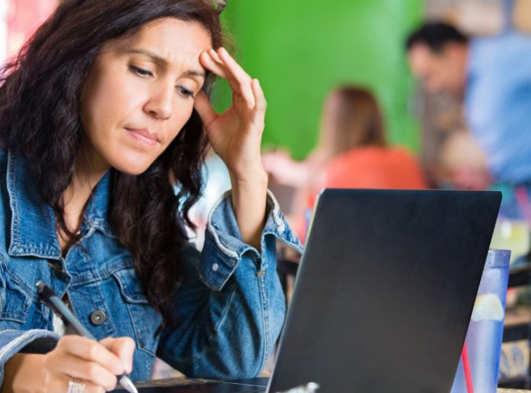 Worried young businesswoman checking finances on computer in restaurant