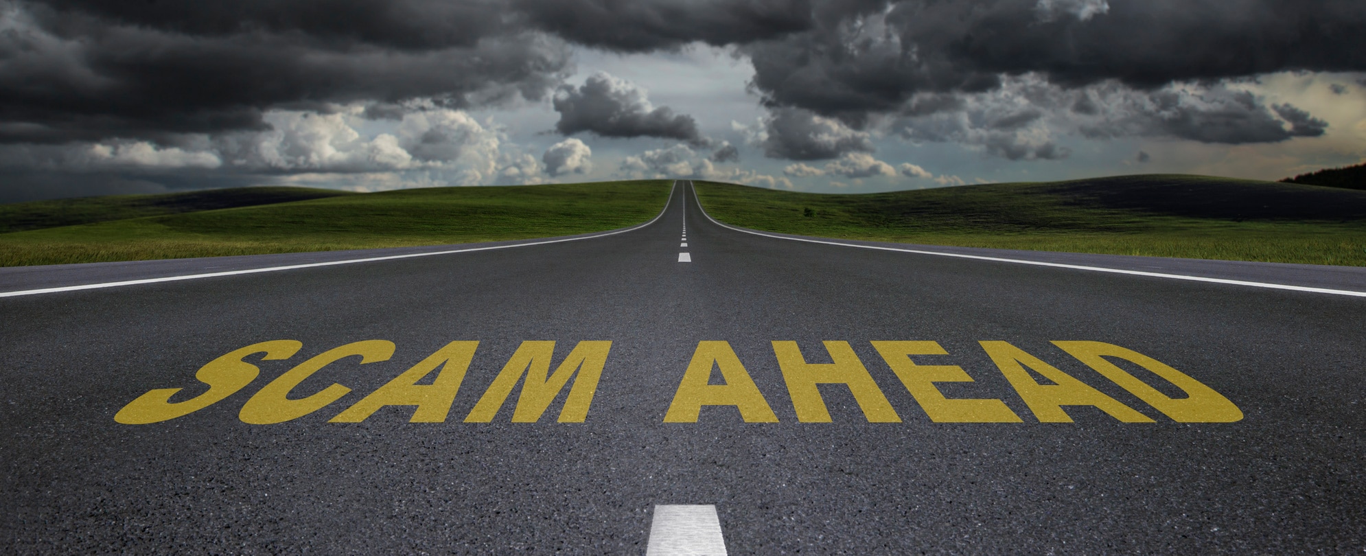 Dark clouds and empty road that reads SCAM AHEAD