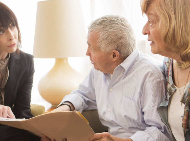 Concerned elderly couple reviewing paperwork with an attorney