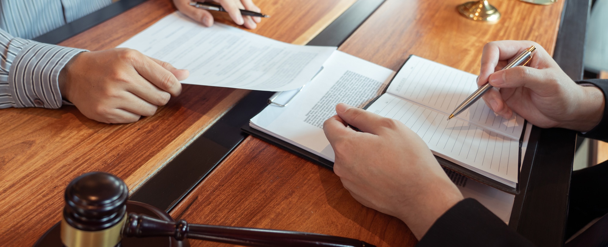 Cropped Hands Of Judge Writing In Book With Businessman At Desk