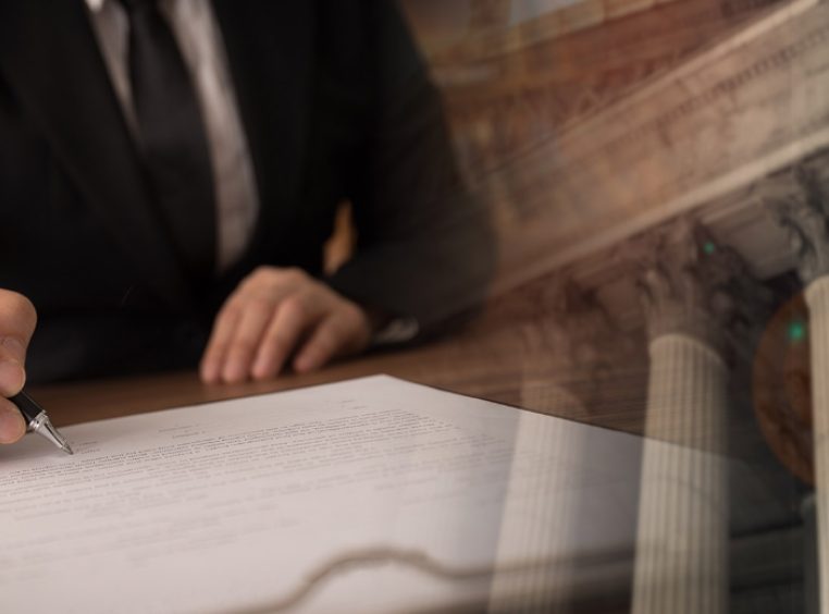 Man in suit writing on a document with fade-in of court building in background