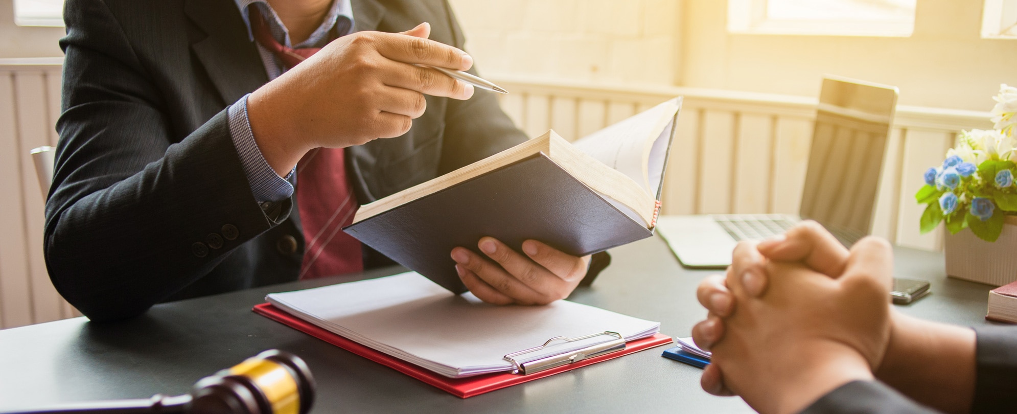 Close up of a lawyer holding a notebook in one hand and a pen in another explaining details of a lawsuit 