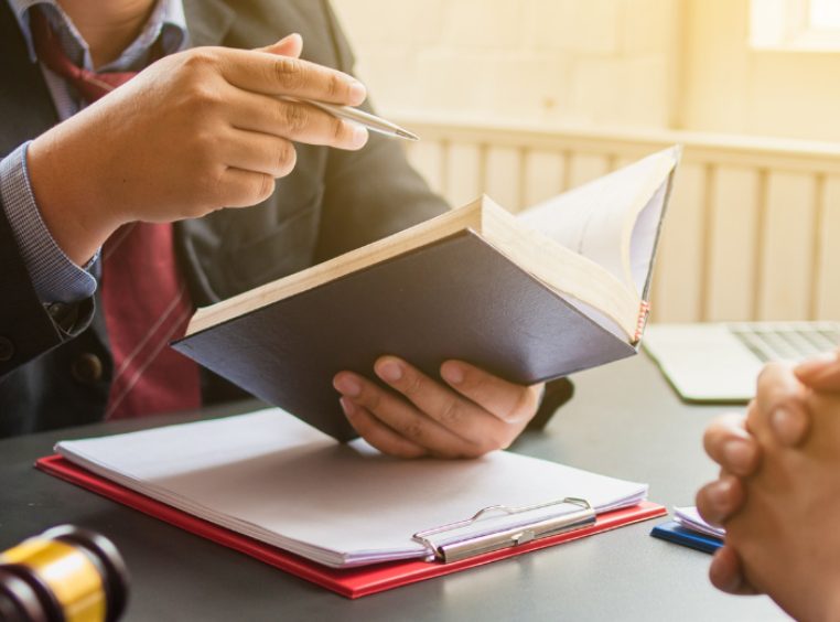 Close up of a lawyer holding a notebook in one hand and a pen in another explaining details of a lawsuit 