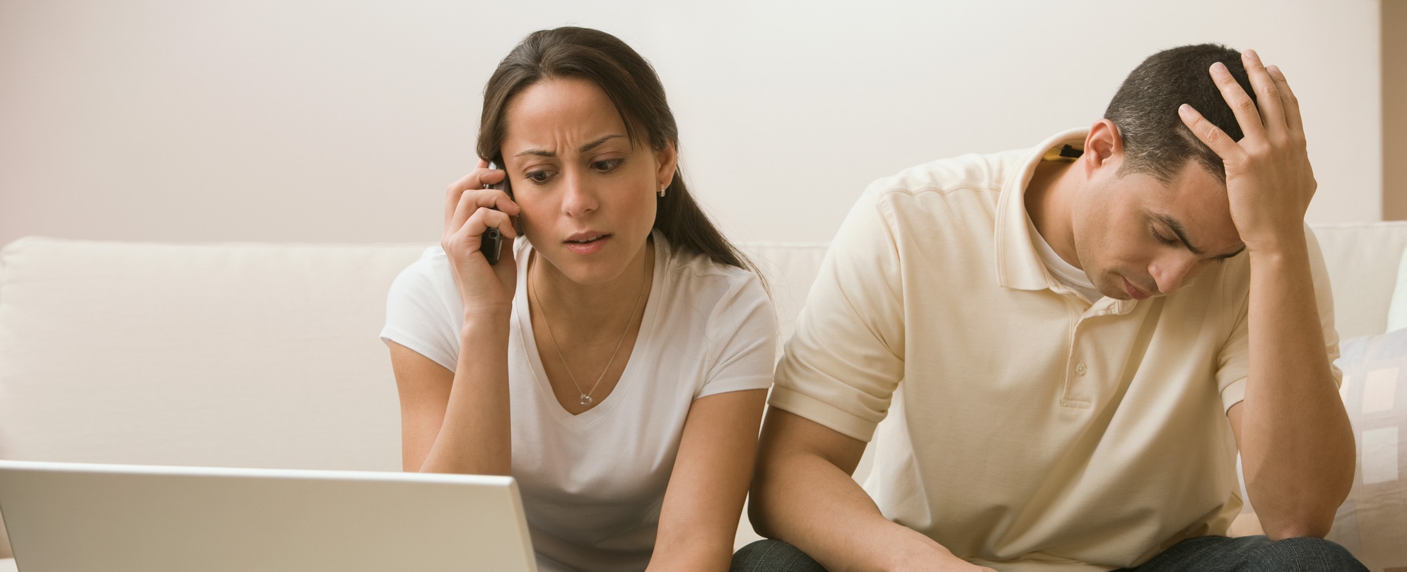 Concerned woman speaks on the phone while man holds head in despair