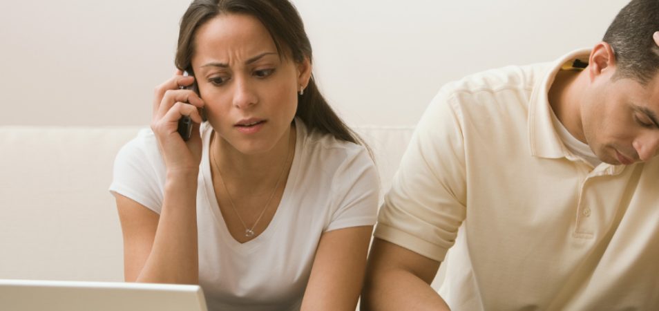 Concerned woman speaks on the phone while man holds head in despair