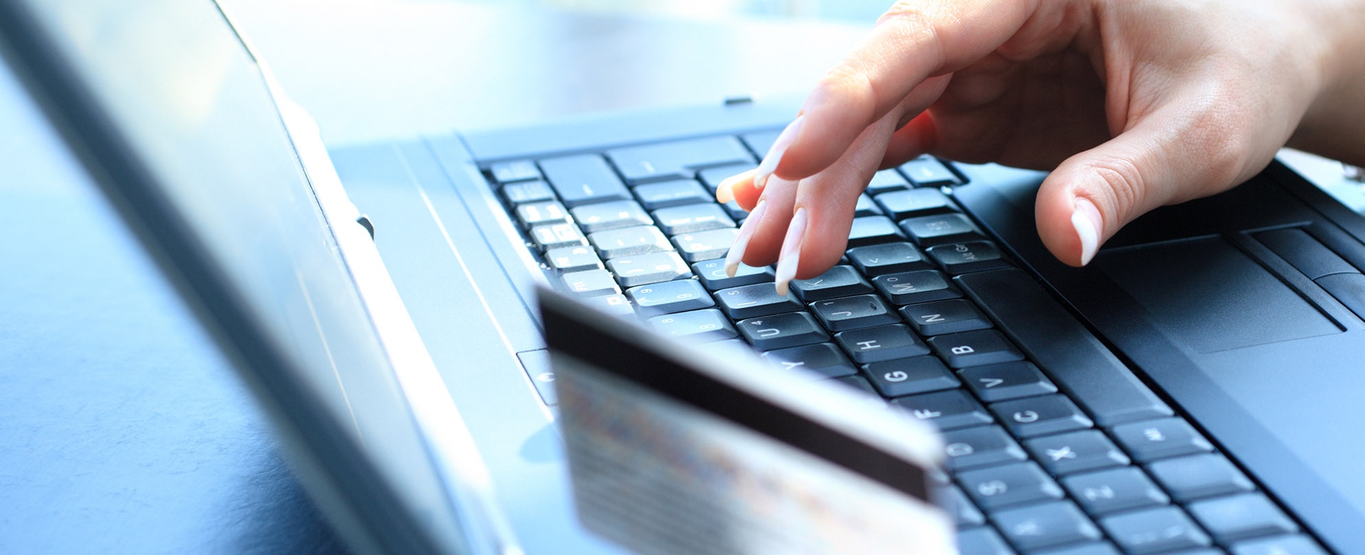 A woman typing her credit card number on a laptop