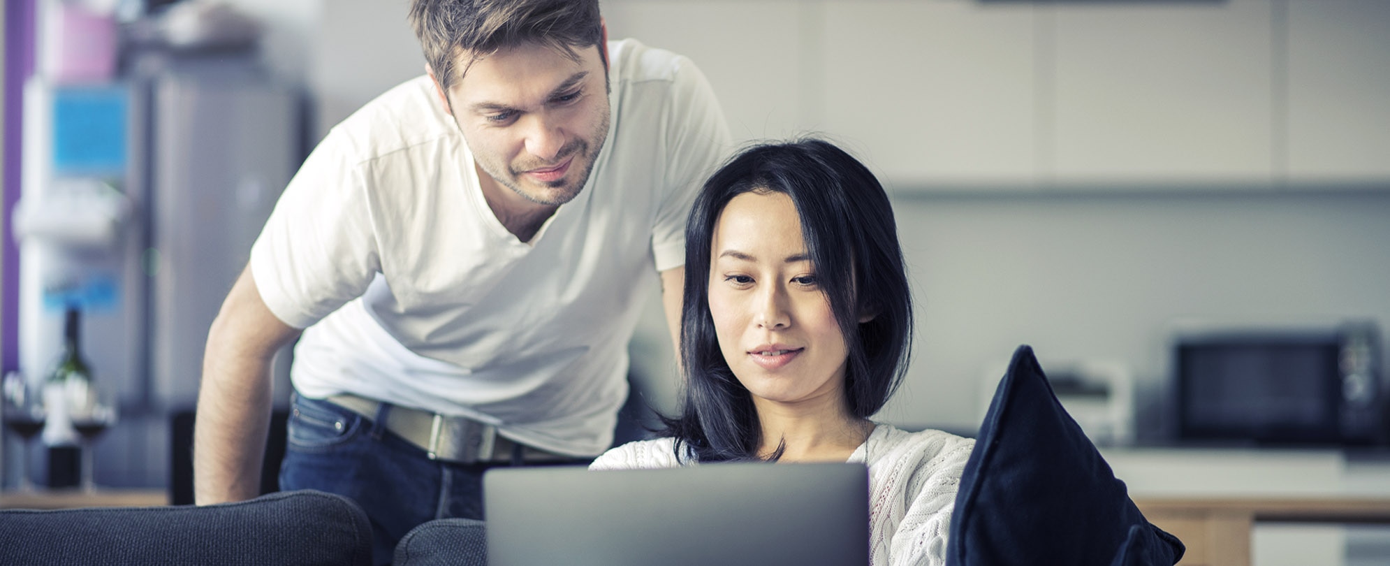 Happy young couple reviewing their eBay account on their laptop 