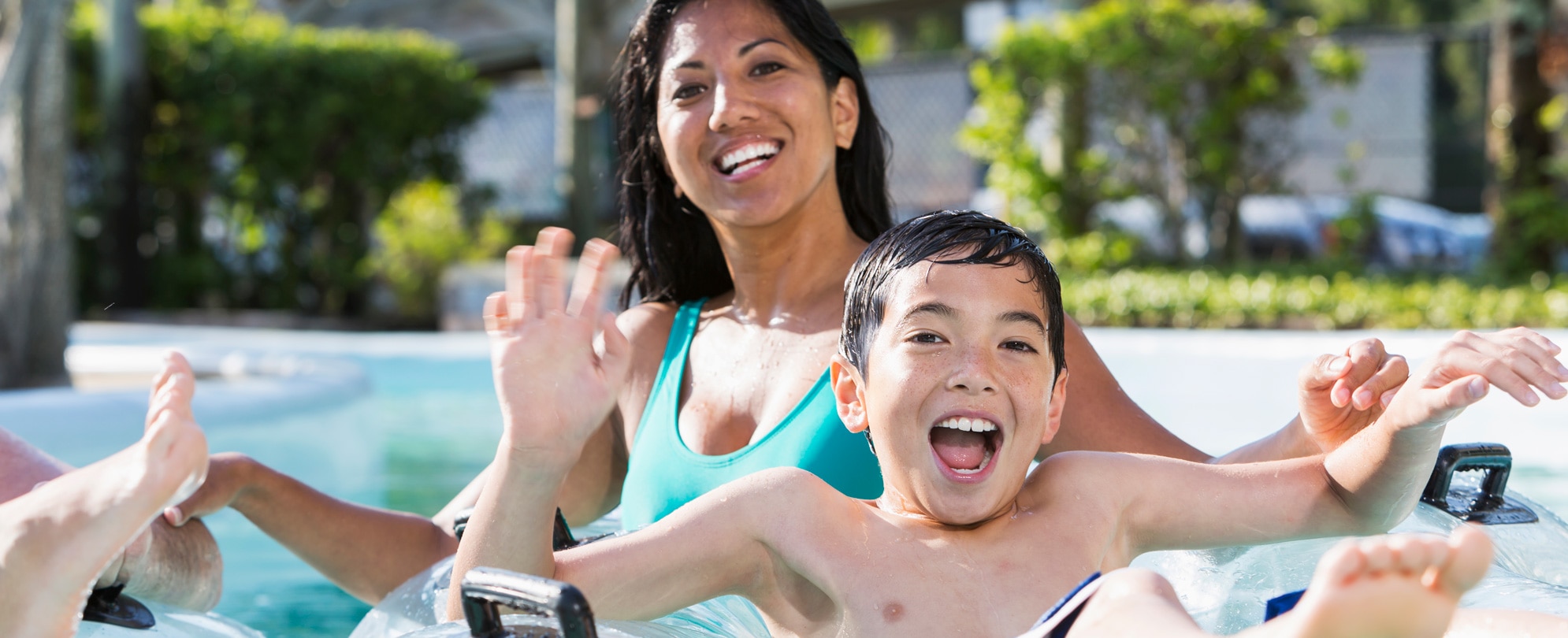 Smiling mother and son on clear pool float posing for a picture in a resort pool 