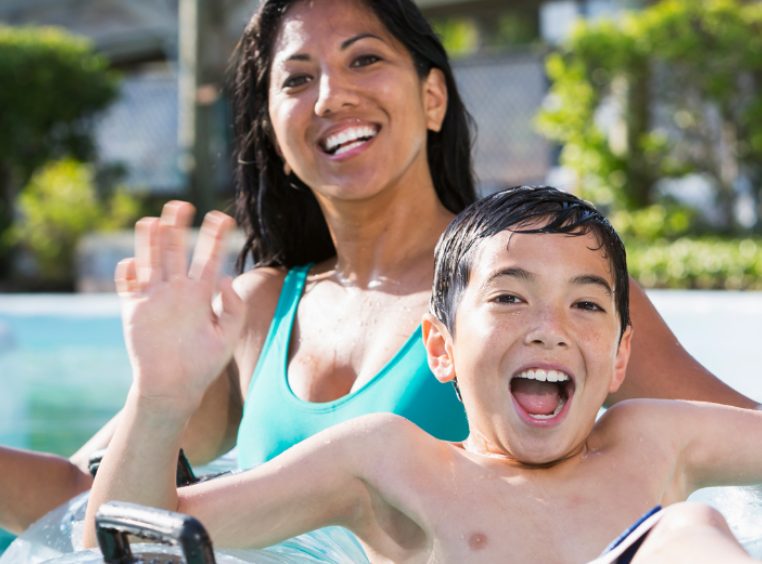 Smiling mother and son on clear pool float posing for a picture in a resort pool 