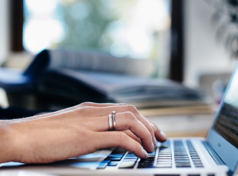 Close up of a woman’s hand typing on a laptop keyboard 