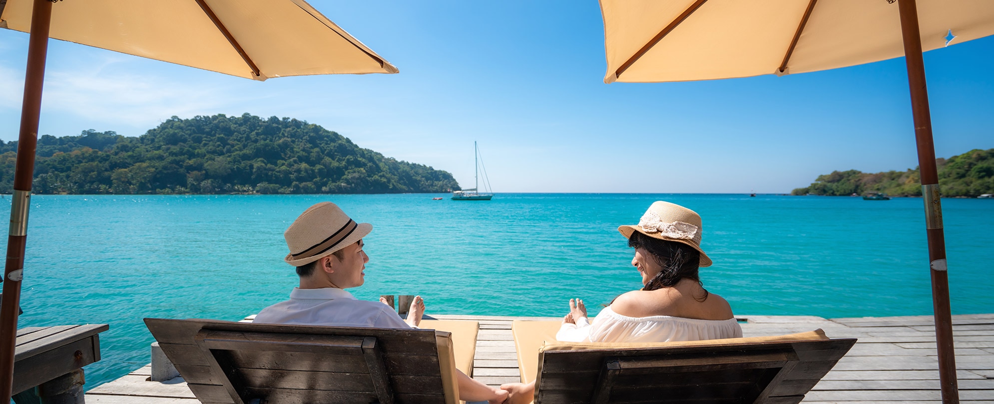 A man and a woman relaxing in a cabana facing the ocean. 
