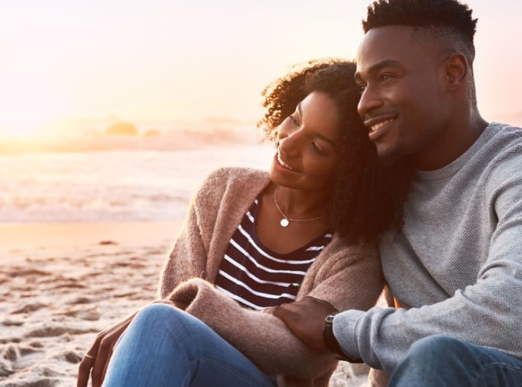 African American couple sitting together on the beach 