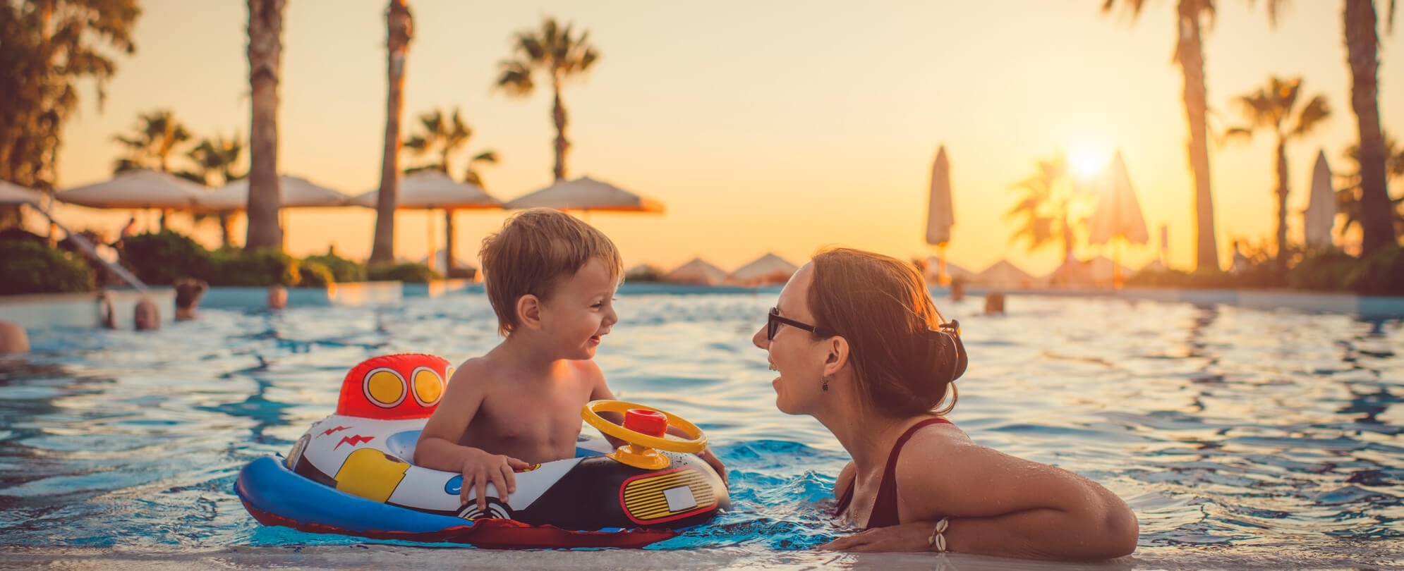 Mother talking to baby son on a pool float 