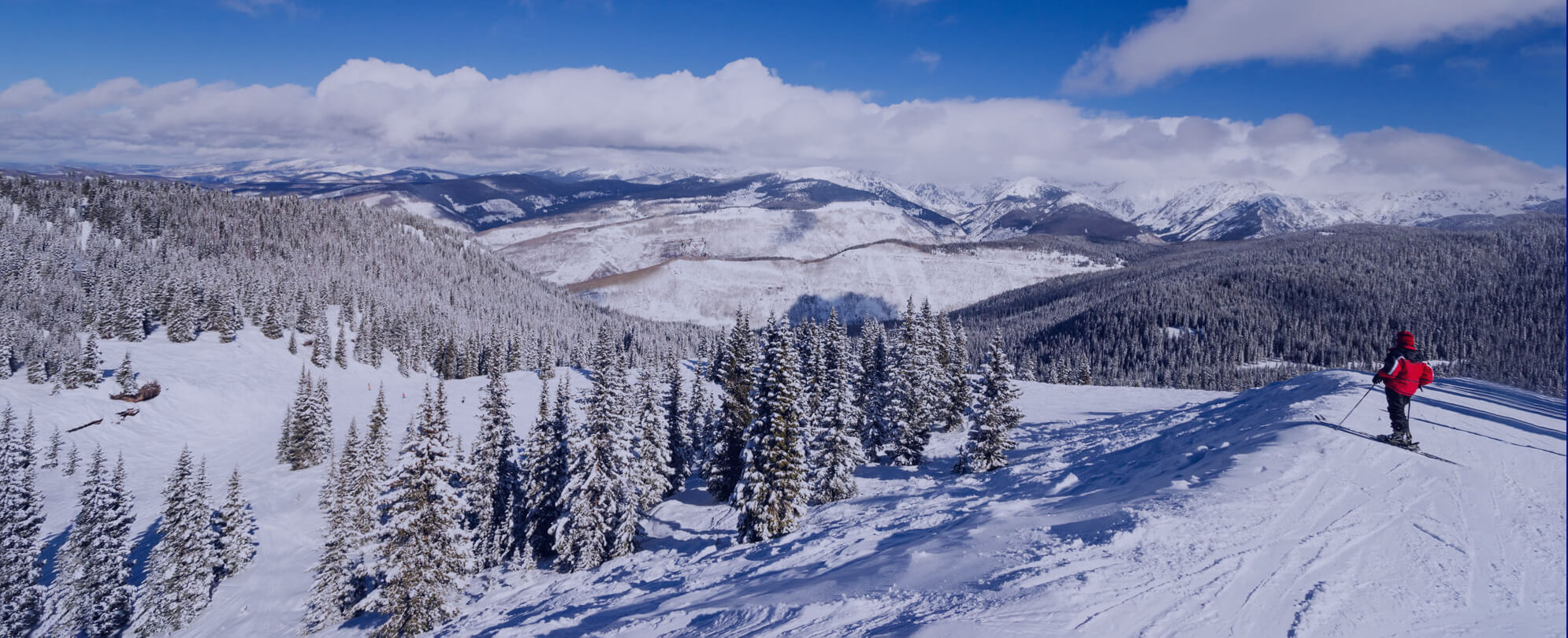 Mountaineer in red jacket overlooking a beautiful winter landscape with snow-covered trees 