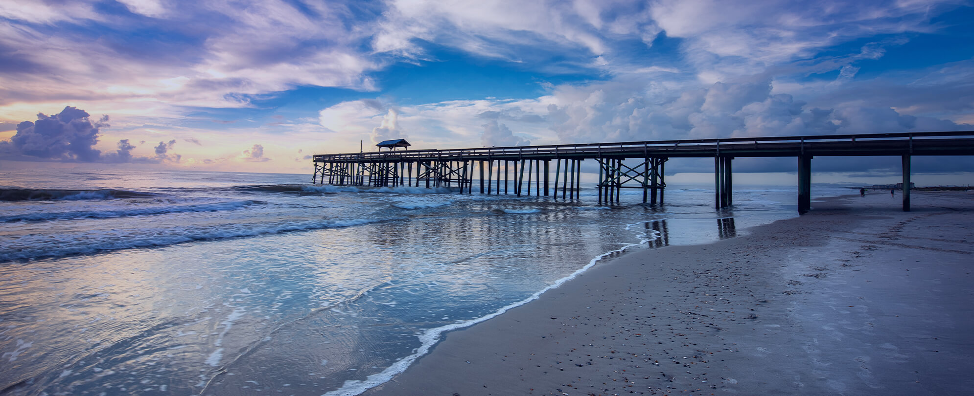 Blue sky and fluffy clouds over beach pier 