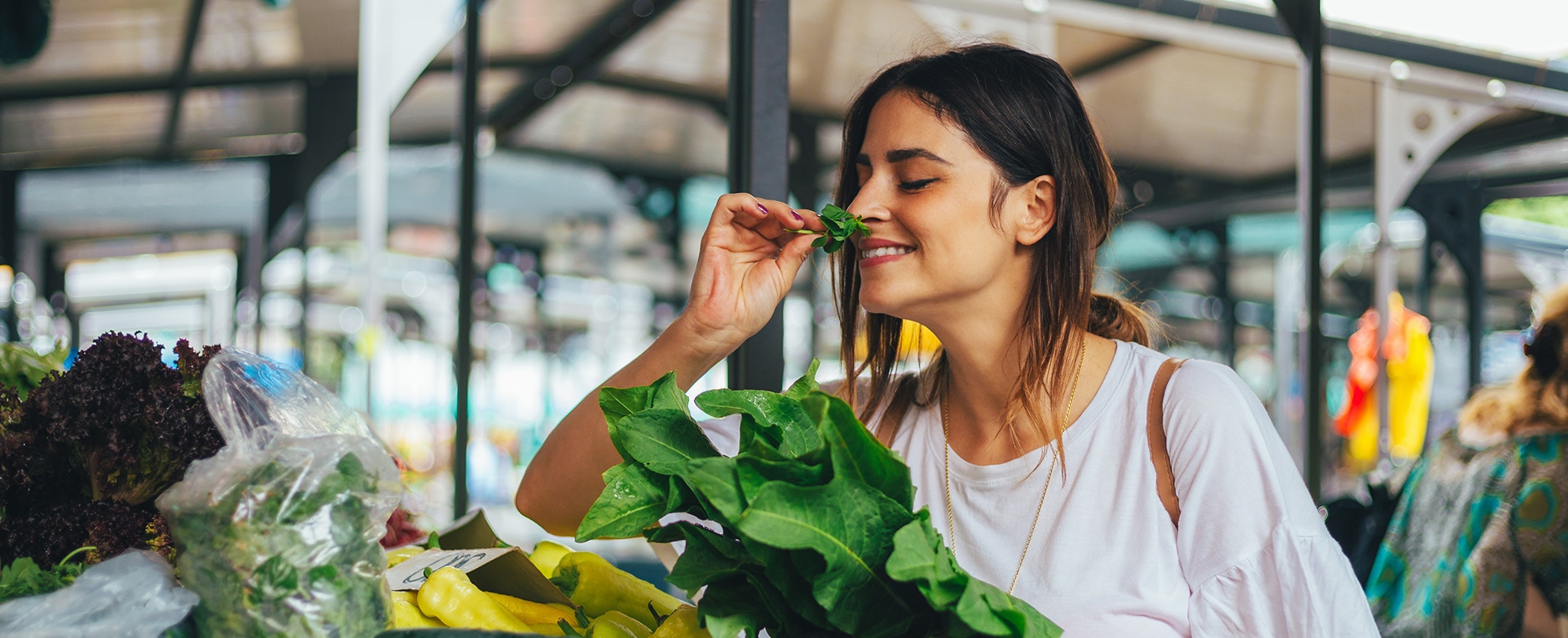 Young woman smelling fresh herbs at a local market