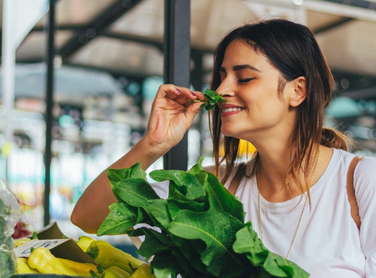 Young woman smelling fresh herbs at a local market