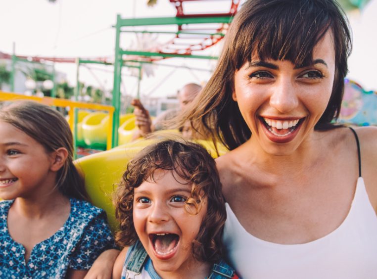 Mother and two daughters laughing on a caterpillar amusement park ride 